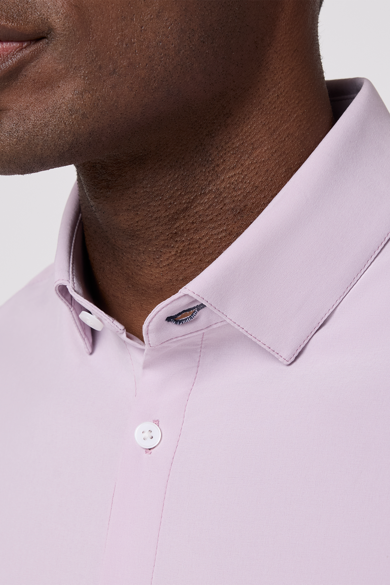Close-up of a person wearing a light purple dress shirt with a collar detail.