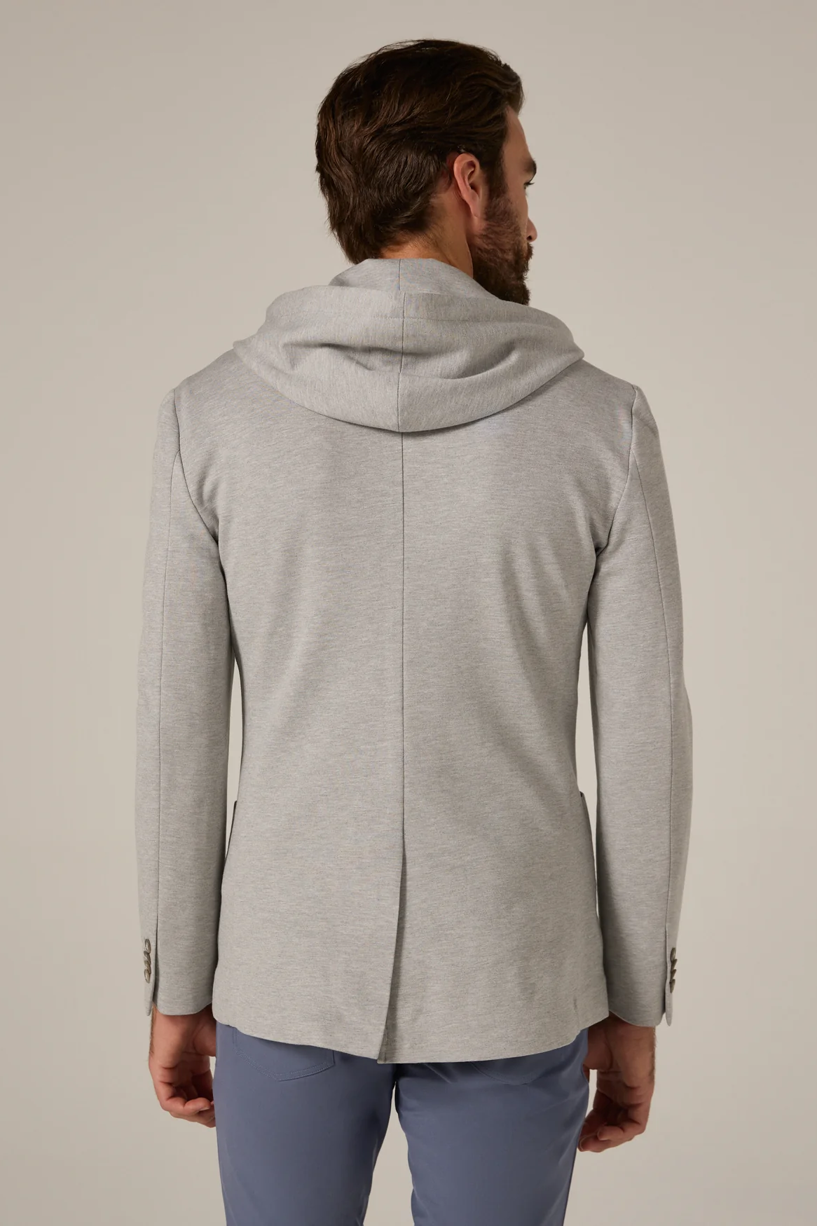 Man wearing a gray hooded jacket on a plain background