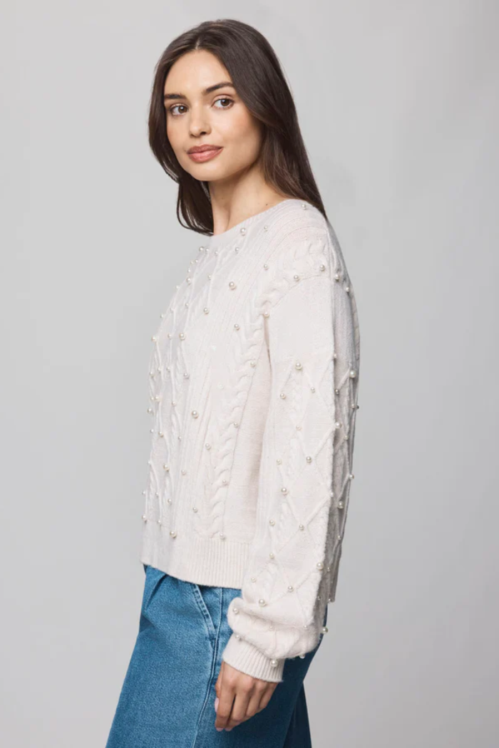 Woman wearing a white sweater with lace details on a gray background