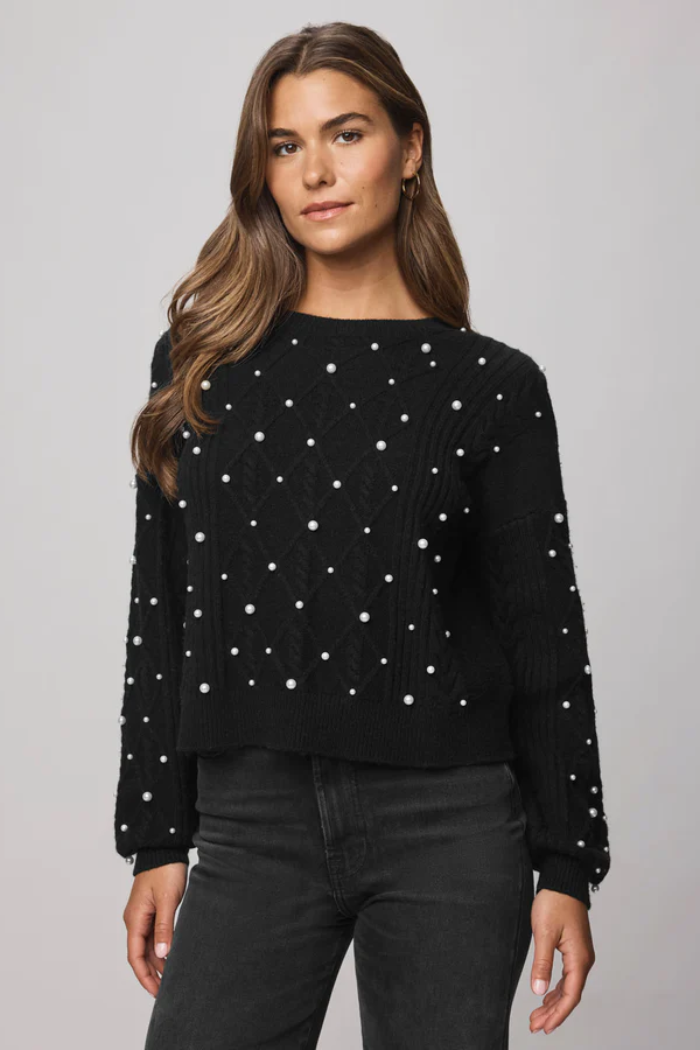 Woman wearing a black sweater with white polka dots on a gray background