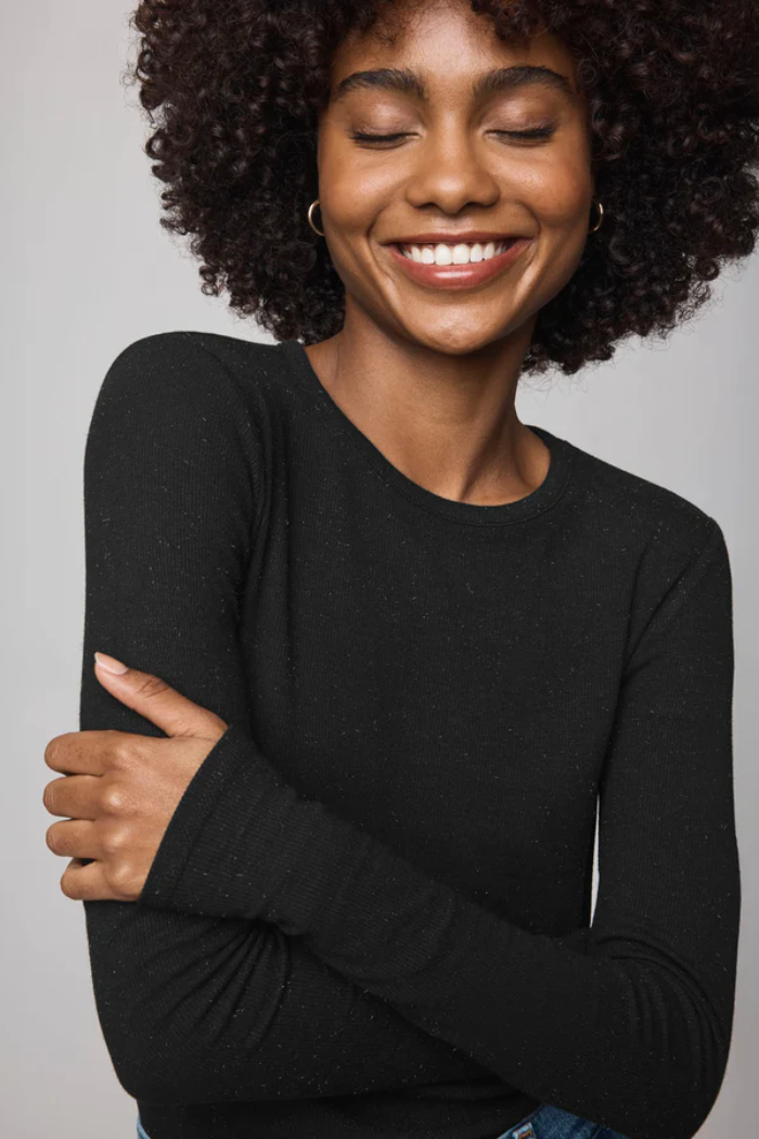 Woman wearing a black long-sleeve shirt against a plain background