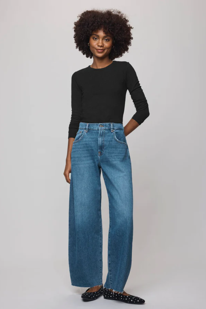 Woman wearing a black top and blue jeans on a white background
