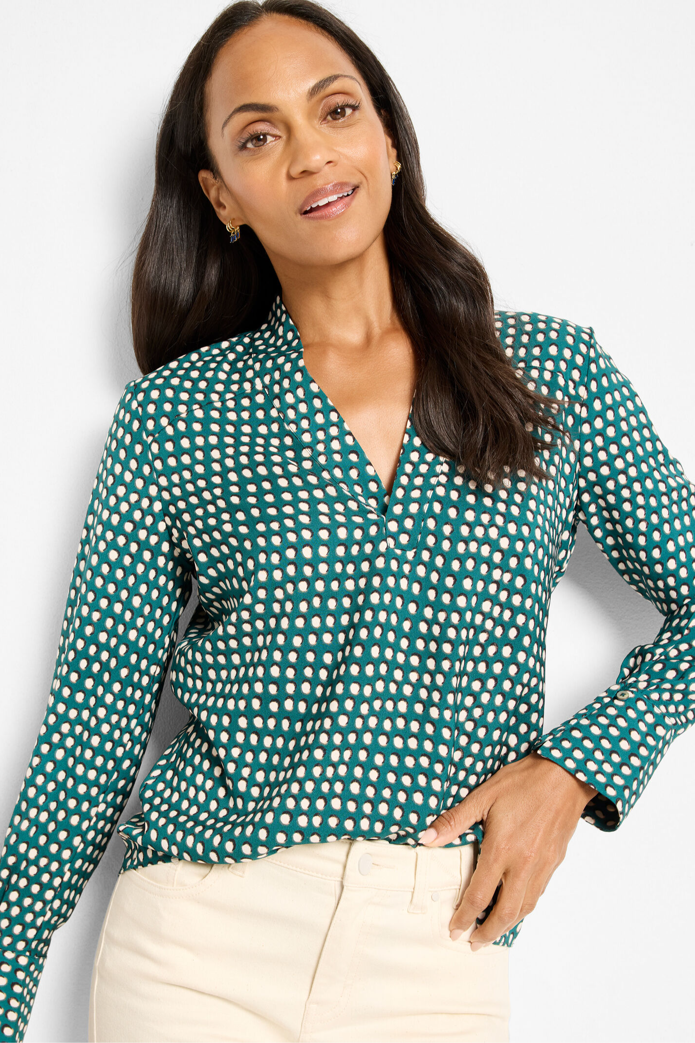 Woman wearing a green and white polka dot blouse against a light background