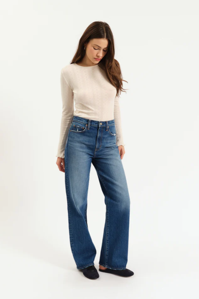 Woman wearing blue jeans and a beige top on a white background