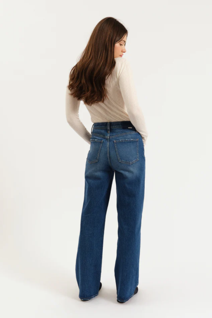 Woman wearing blue jeans and a beige sweater on a white background