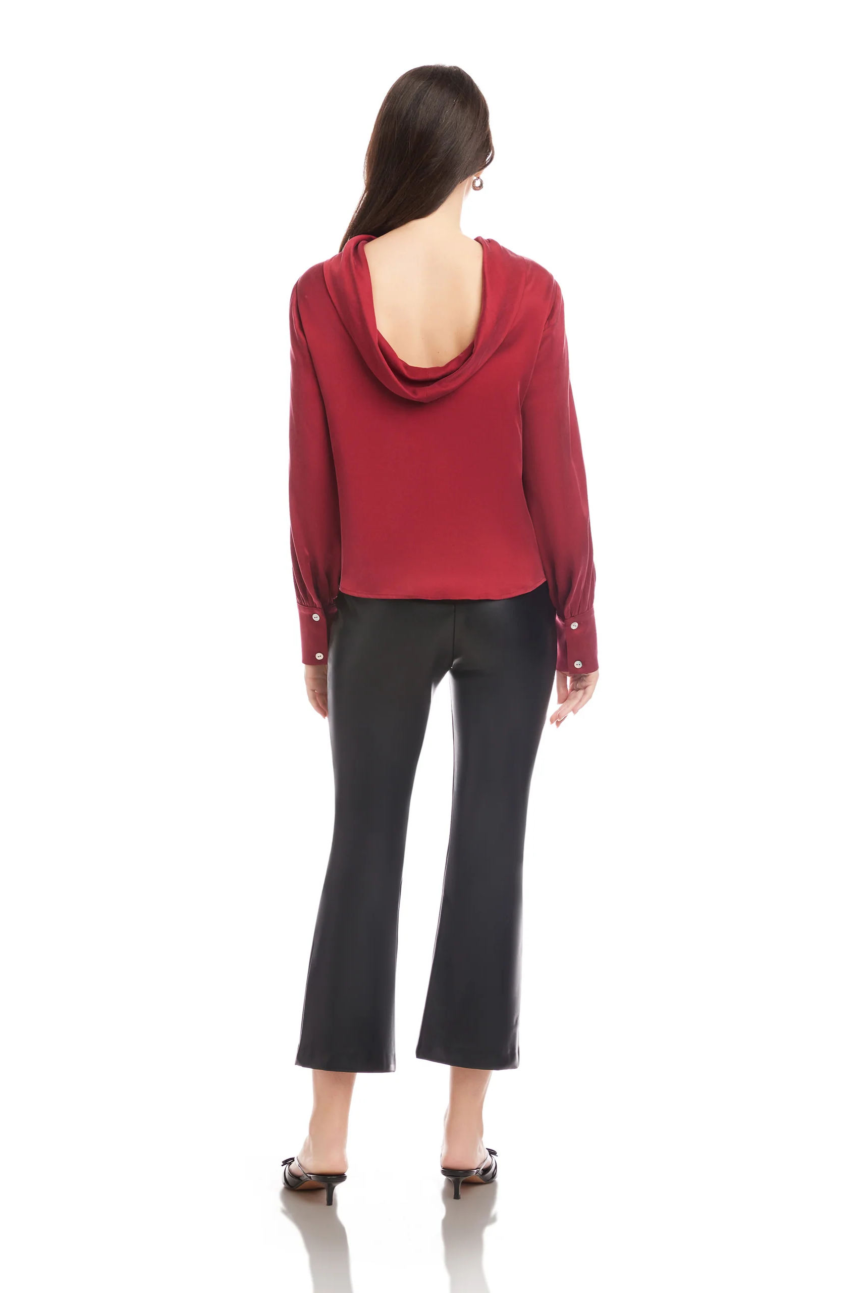 Person wearing a red hoodie with open back and black pants on a white background