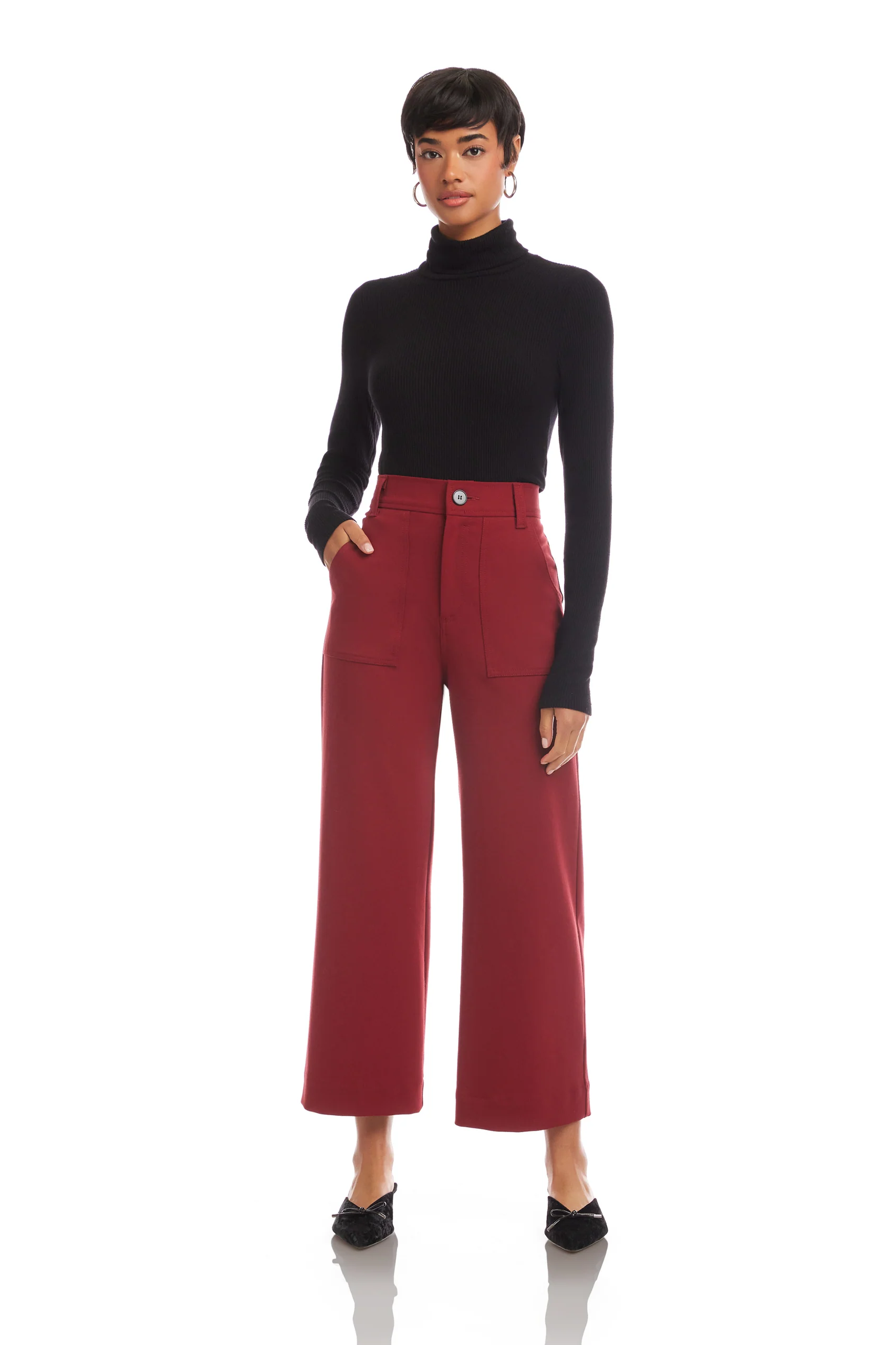 Woman wearing a black turtleneck and red pants on a white background