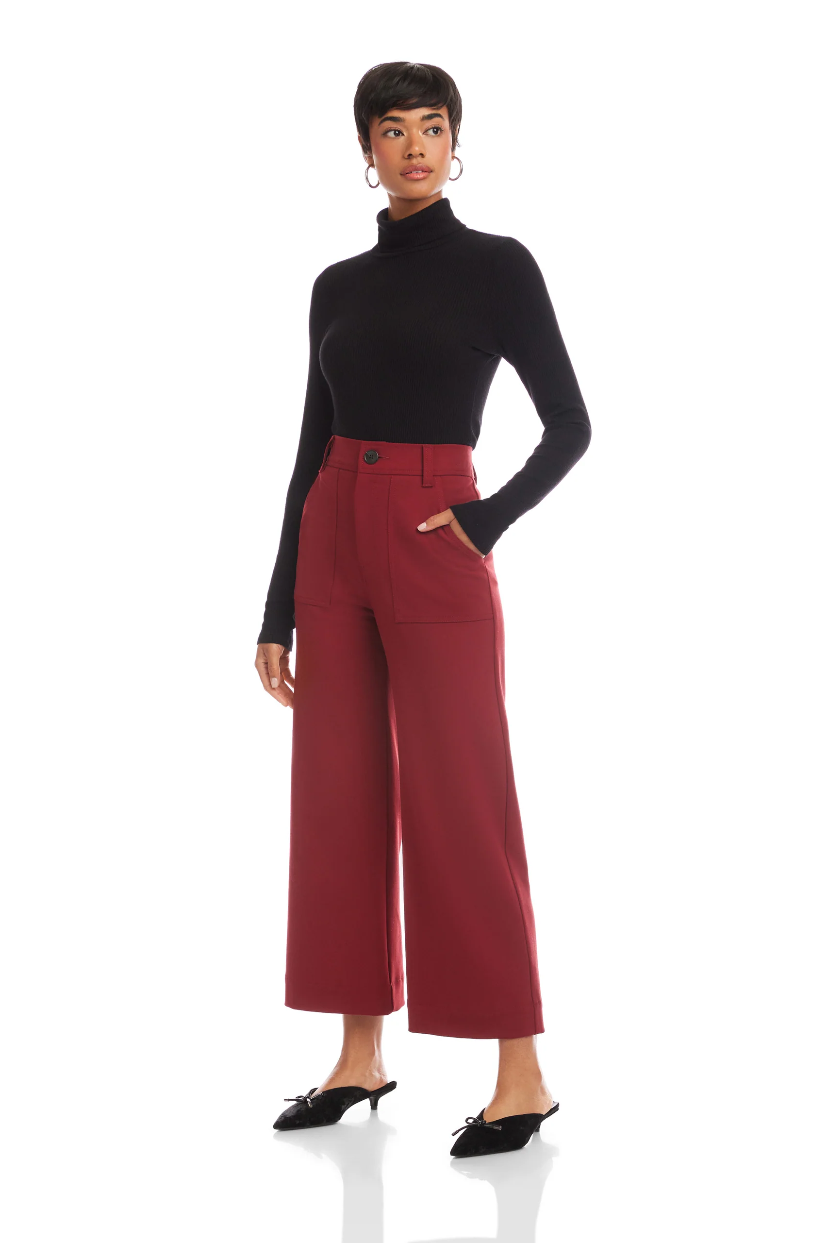 Woman wearing a black turtleneck and red pants on a white background