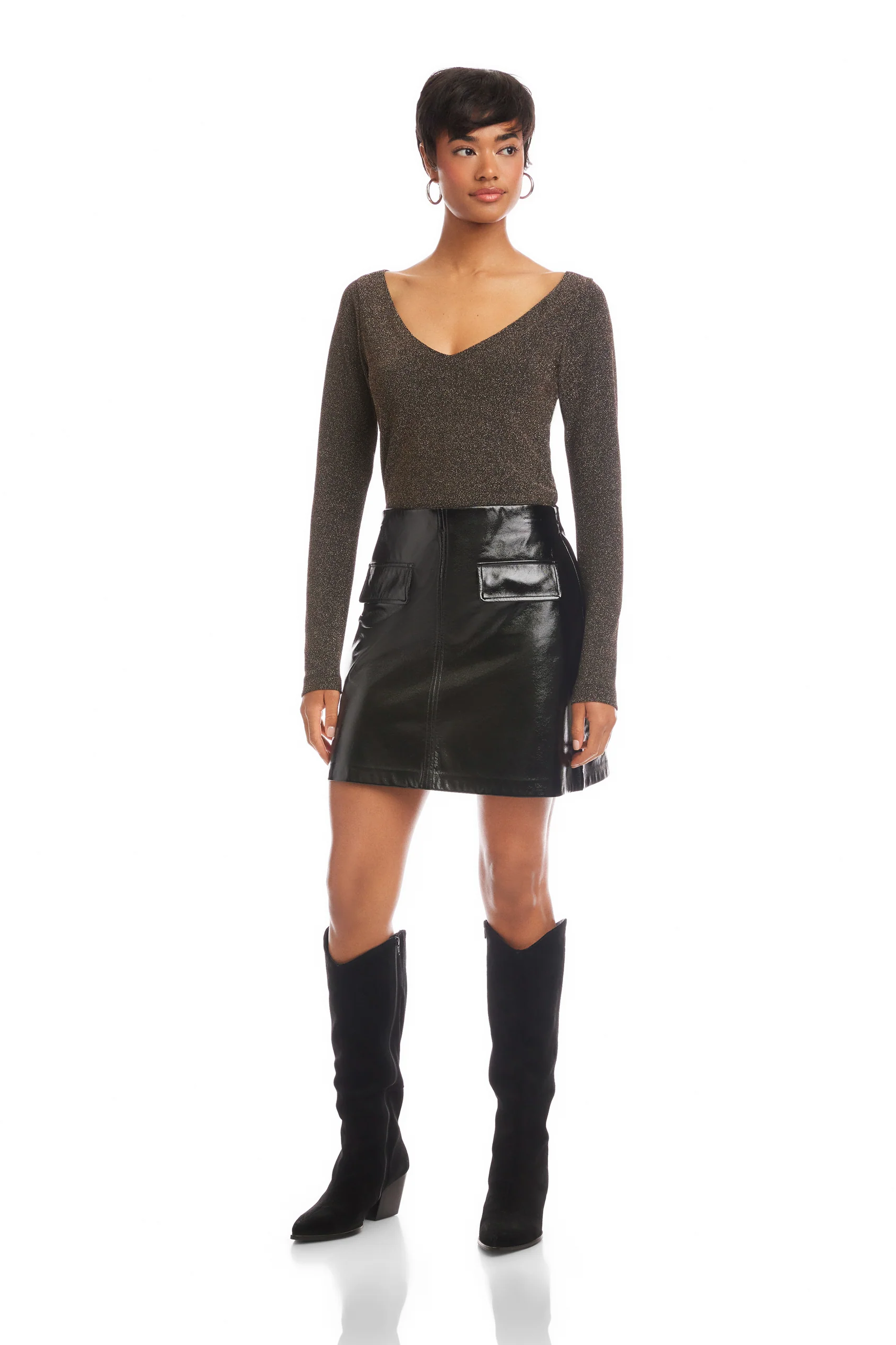 Woman wearing a brown long-sleeve top and black leather skirt with knee-high boots on a white background