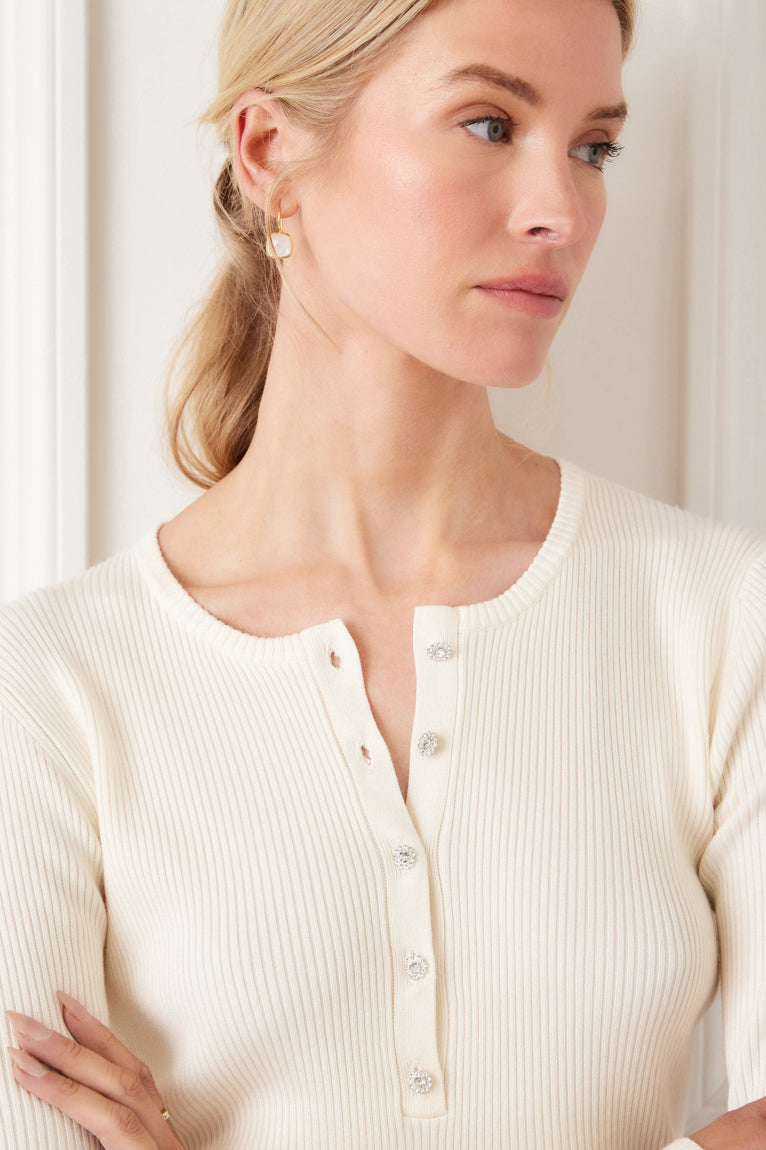 Woman wearing a cream ribbed cardigan against a white background