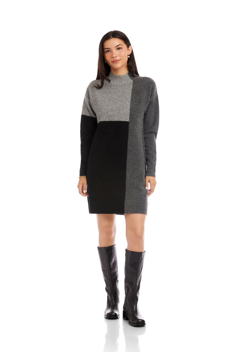 Woman wearing a gray and black color-blocked dress with black knee-high boots on a white background