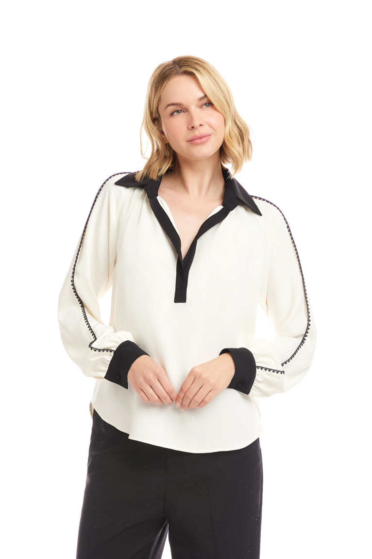 Woman wearing a white blouse with black accents on a white background