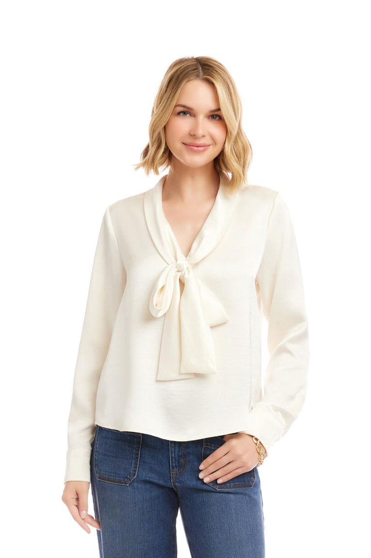 Woman wearing a white blouse with a tie detail and blue jeans on a white background