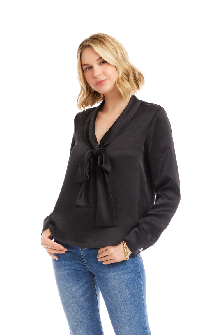 Woman wearing a black blouse with a bow detail and blue jeans on a white background
