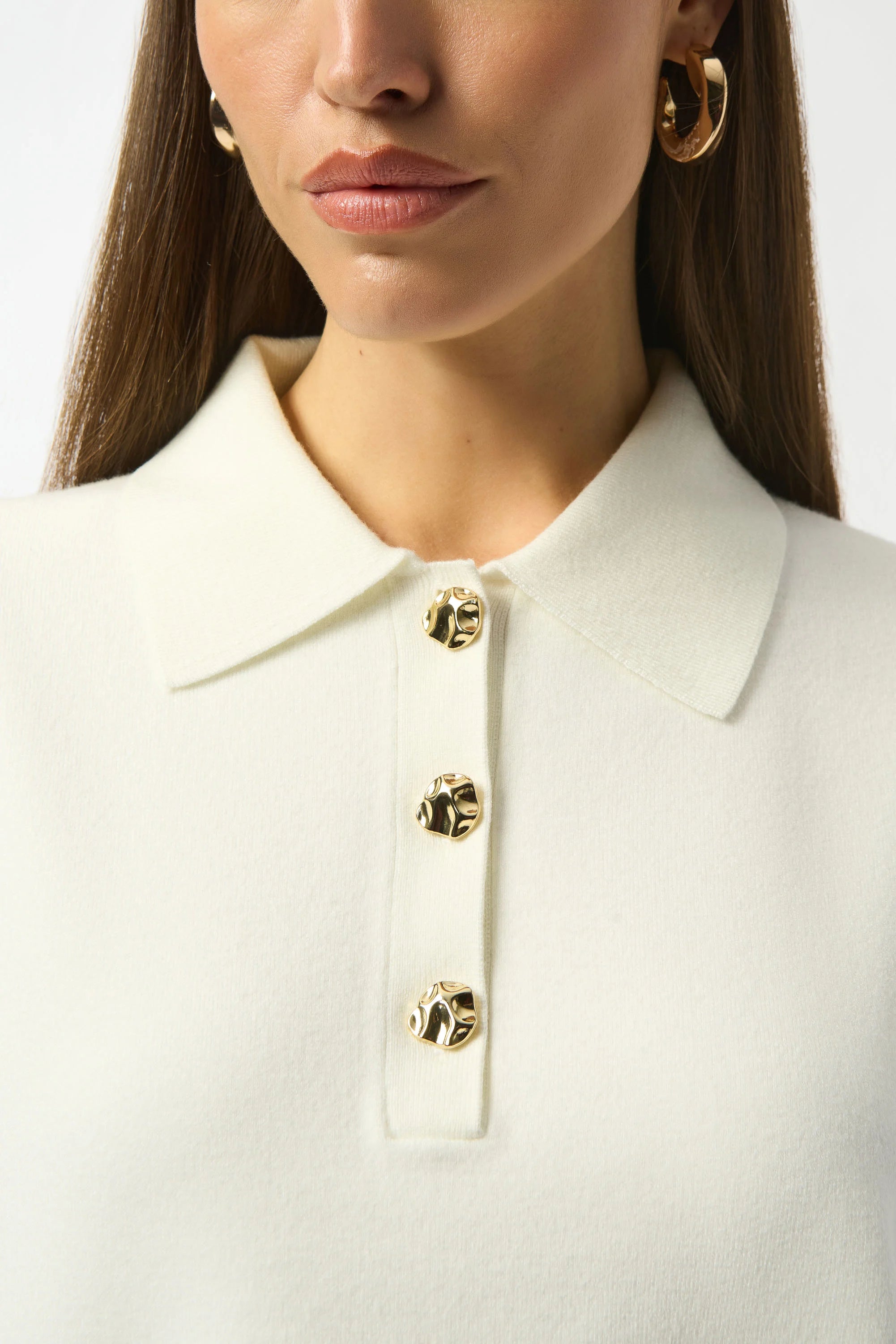 Close-up of a person wearing a white coat with gold buttons on a plain background