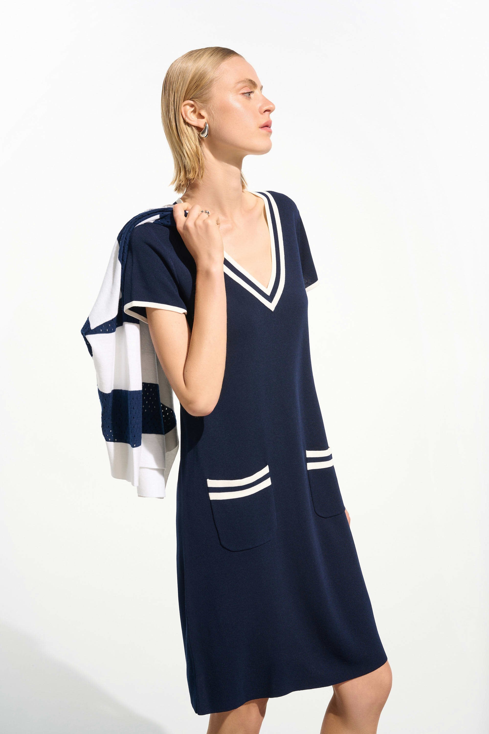Woman wearing a navy dress with white accents on a white background