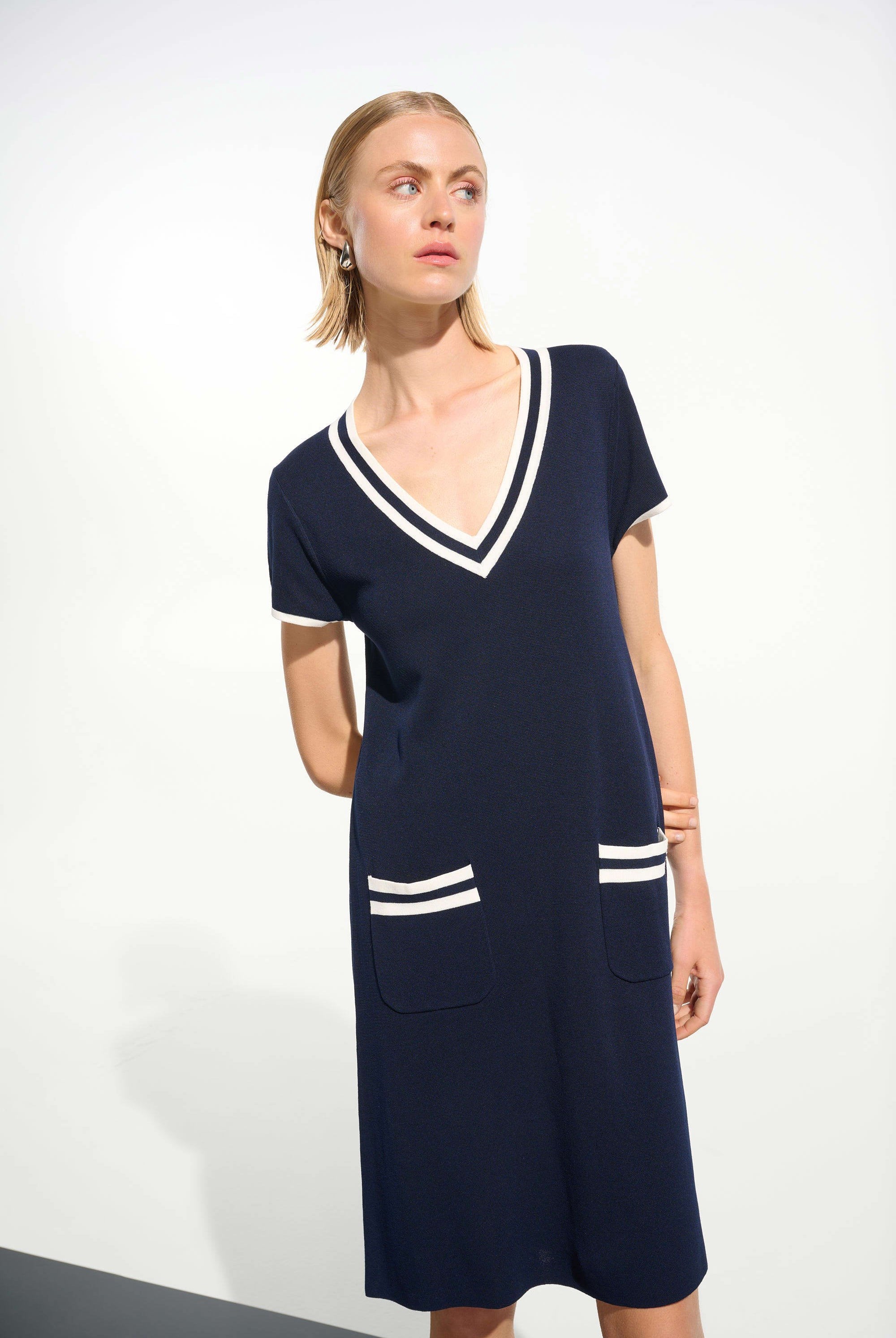 Woman wearing a navy dress with white accents on a white background