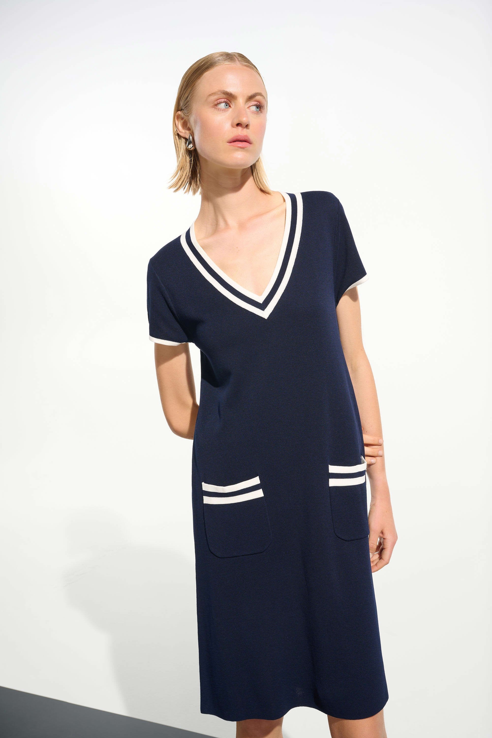 Woman wearing a navy dress with white accents on a white background