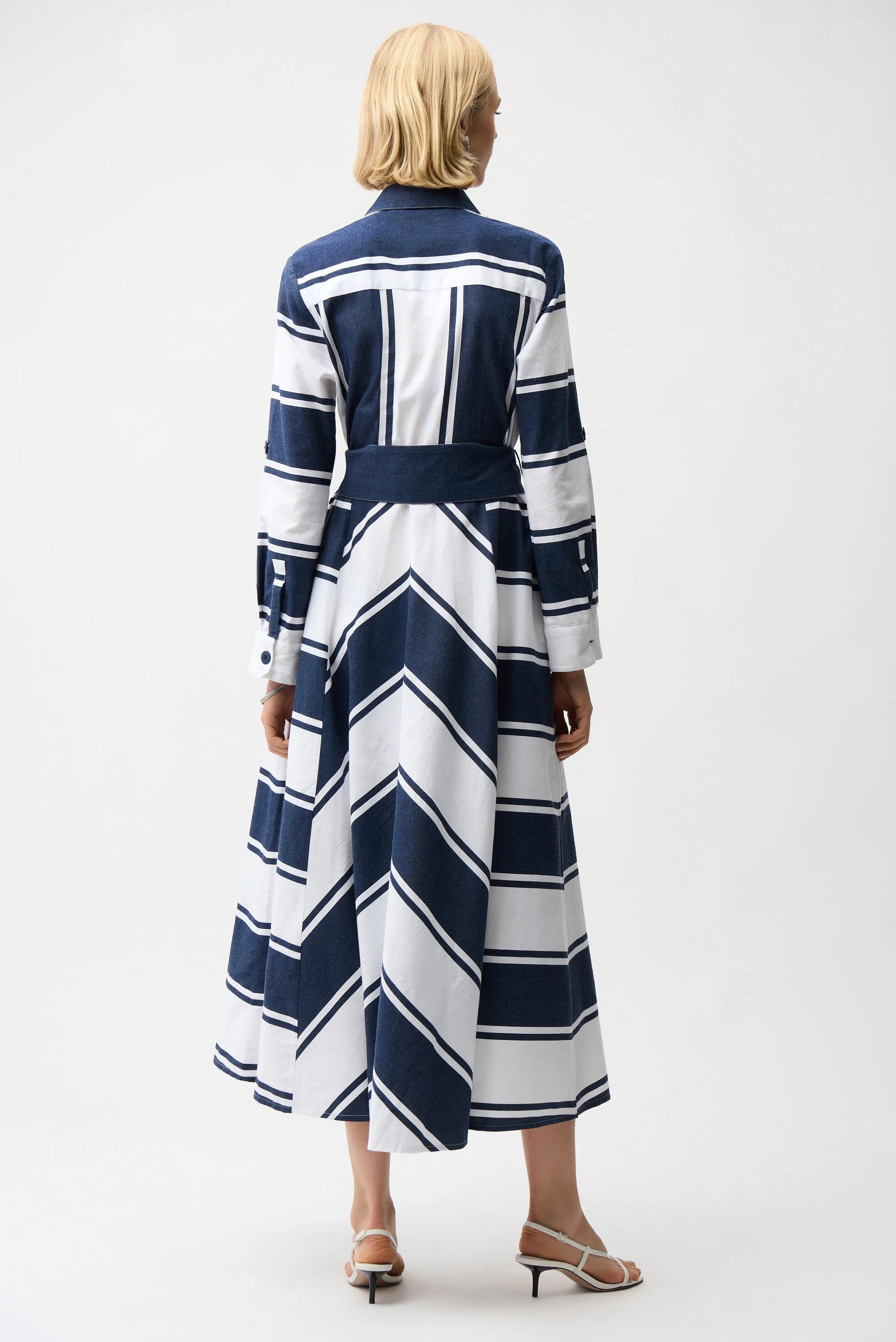 Woman wearing a long, navy and white striped dress on a white background