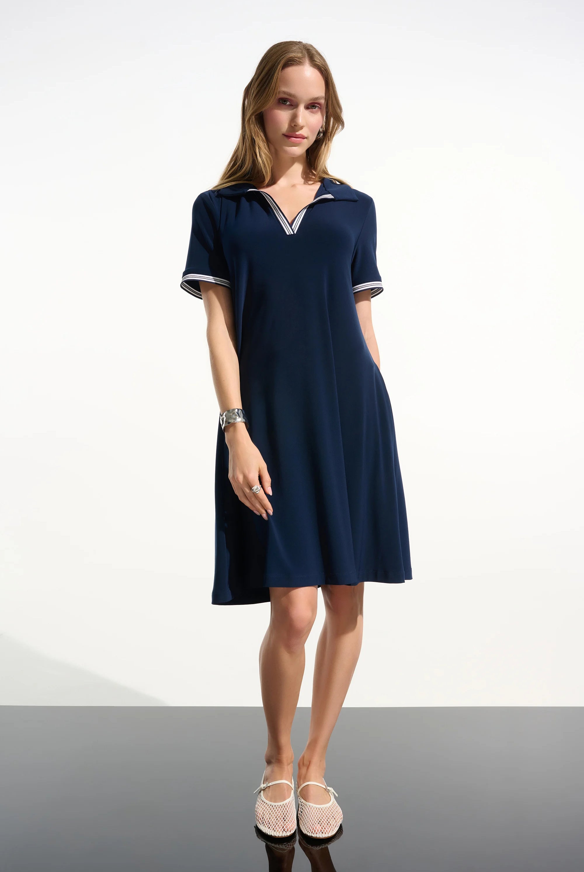 Woman wearing a navy blue dress with white trim on a white background