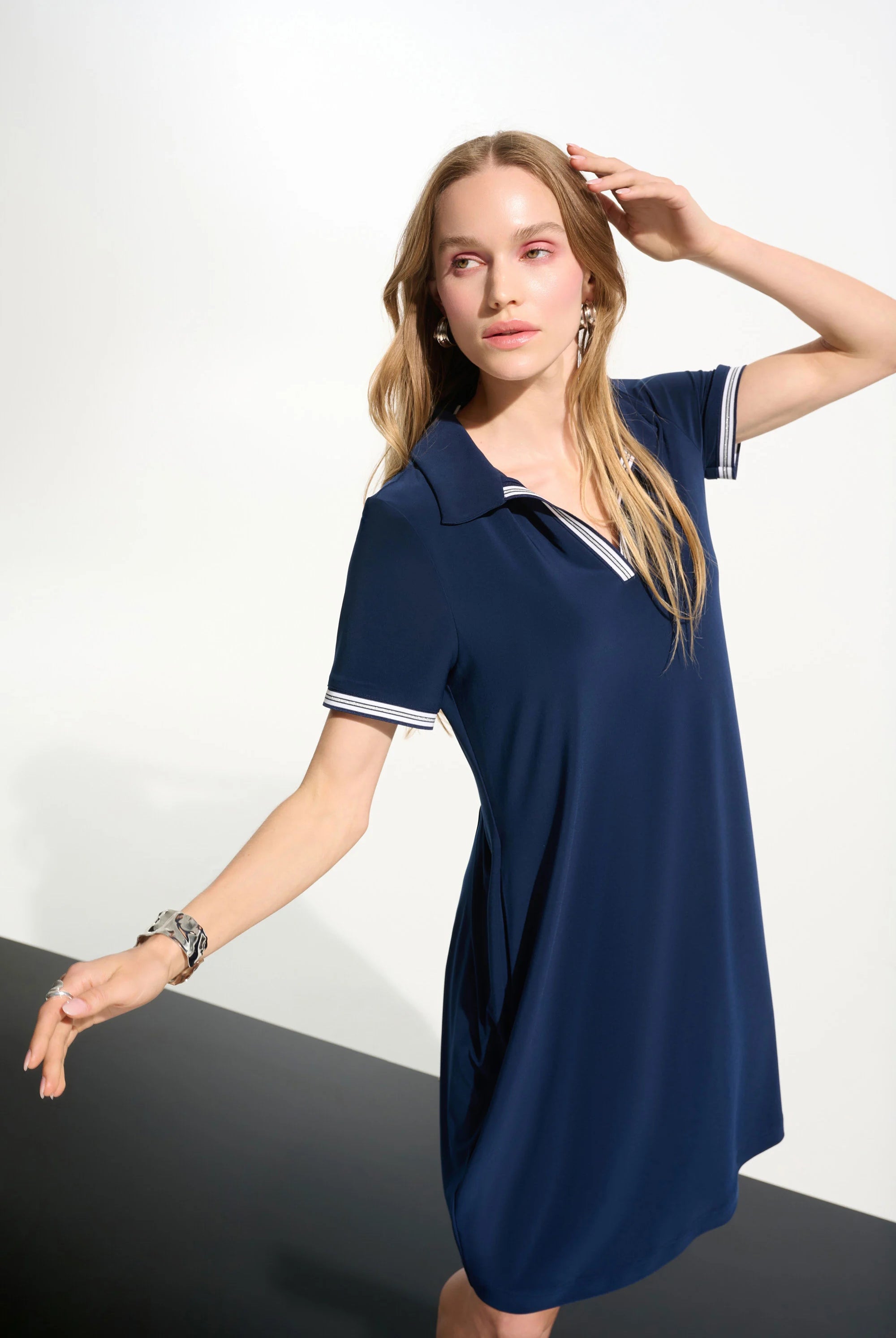 Woman wearing a navy blue dress with white trim on a white background
