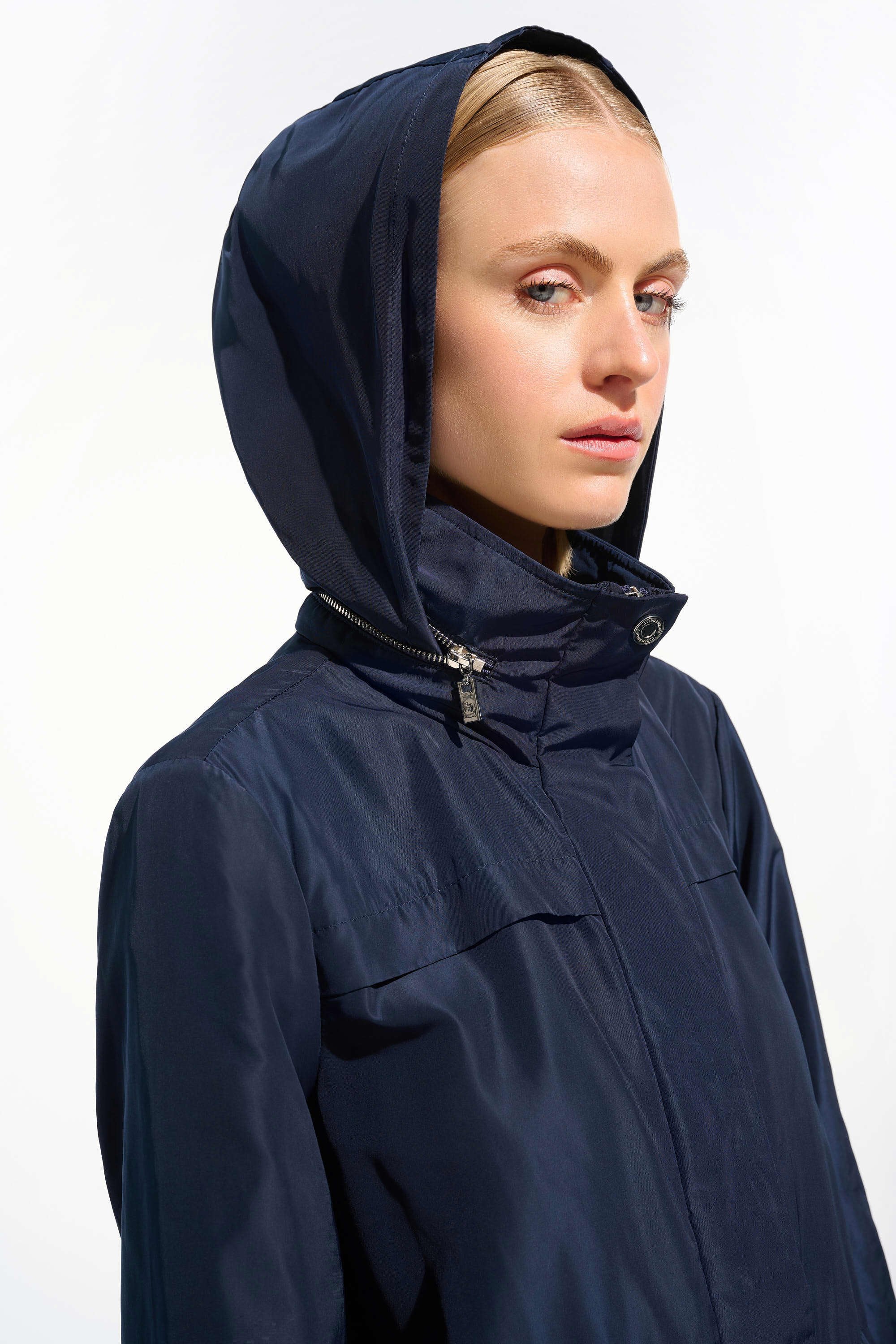 Person wearing a navy blue raincoat with a hood on a white background