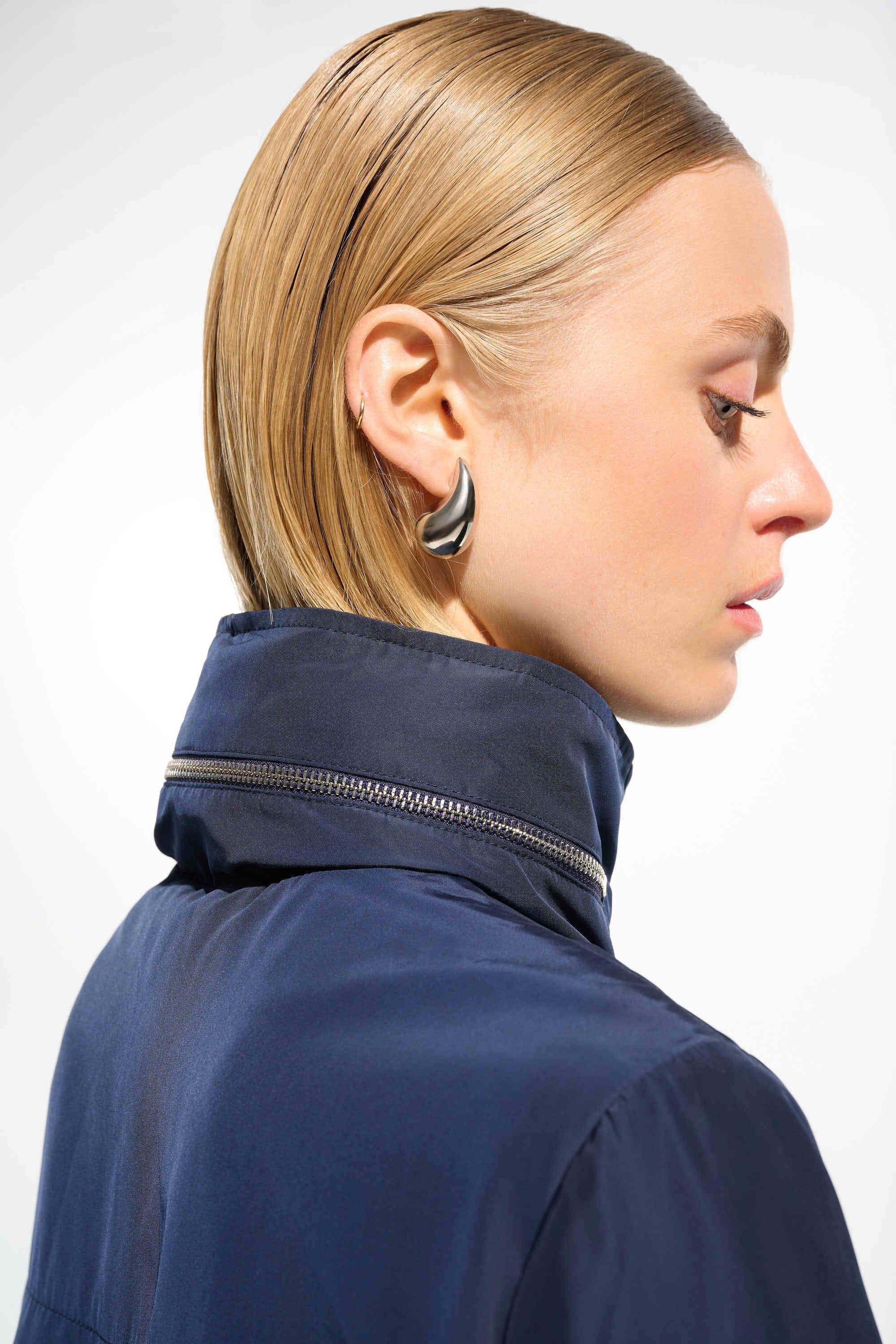 Woman wearing a navy blue jacket with a white background