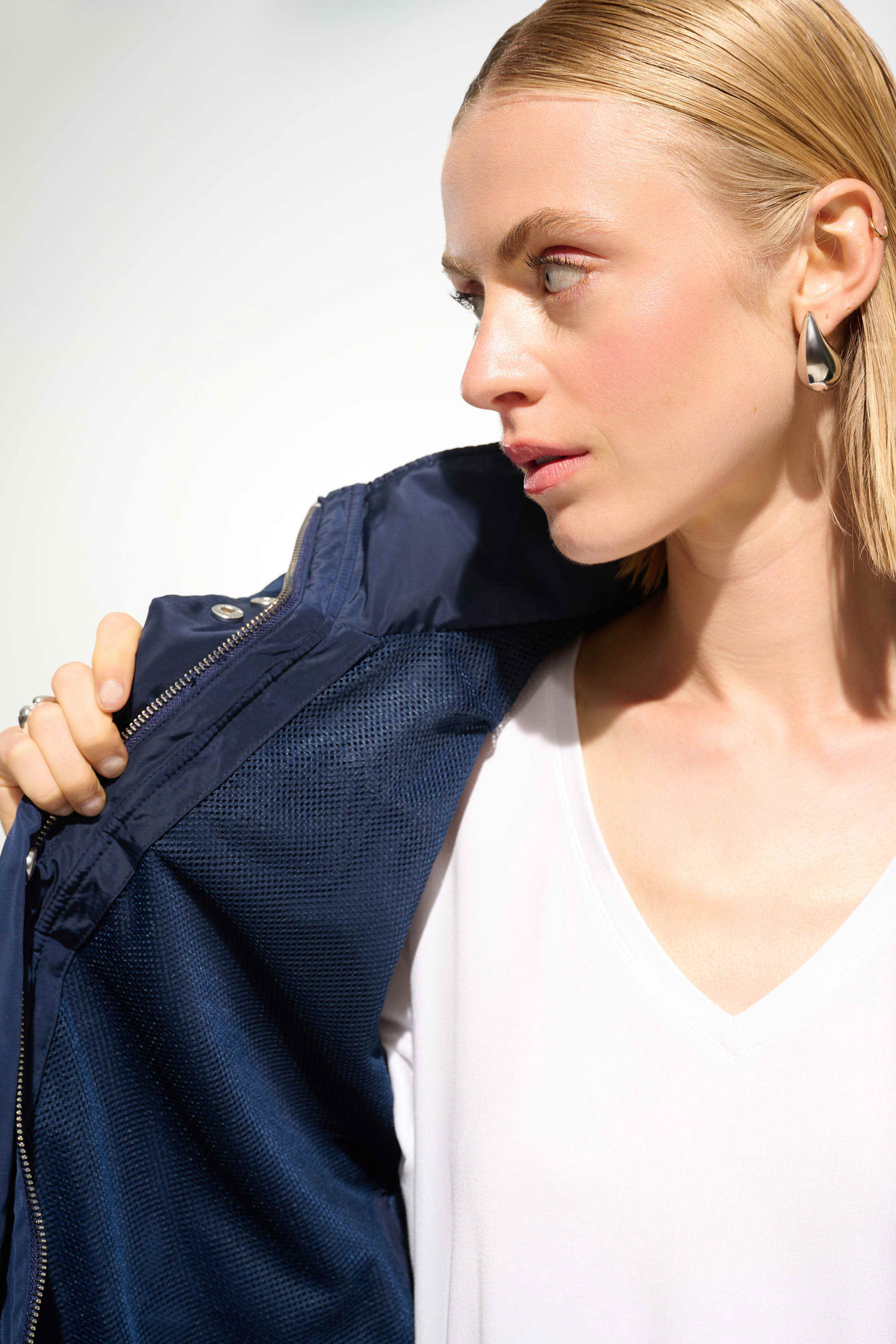 Woman holding a navy blue jacket against a white background