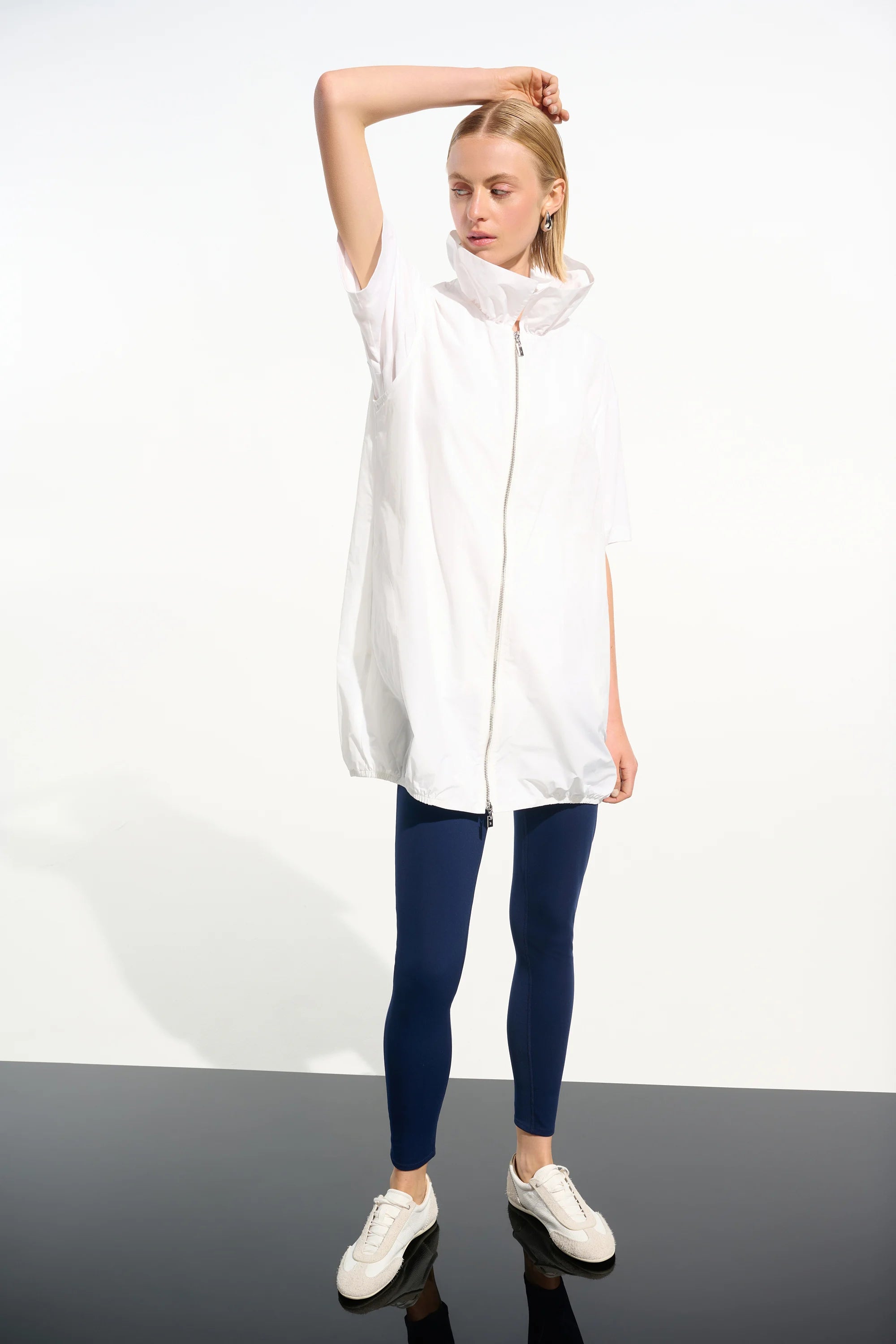 Woman wearing a white sleeveless jacket with a hood on a white background