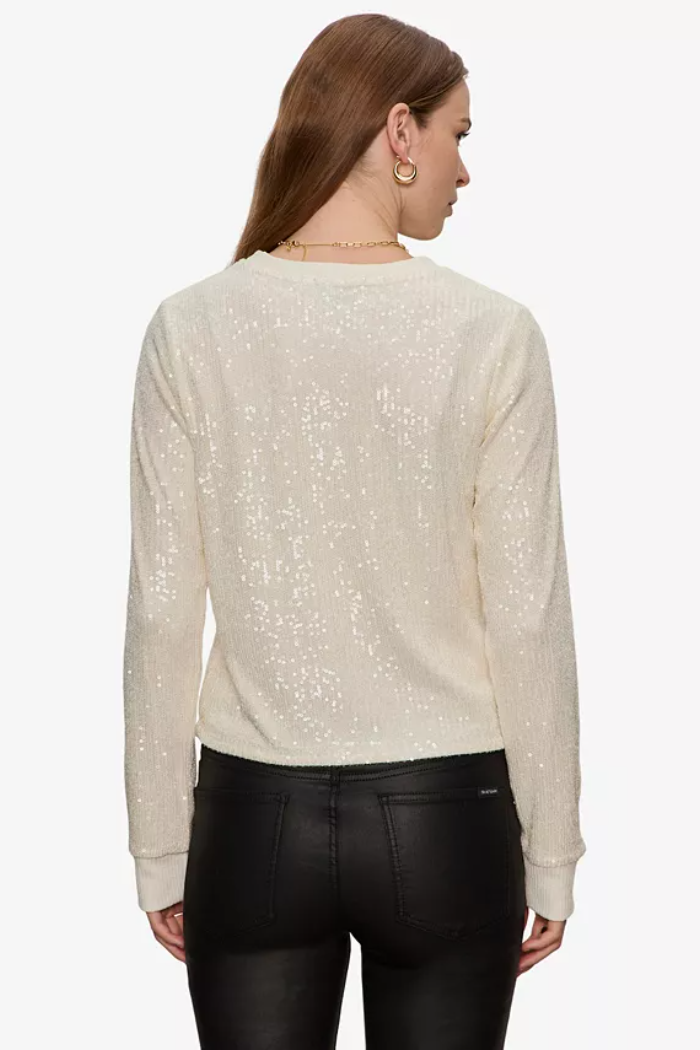 Woman wearing a beige sweater with subtle pattern on a white background