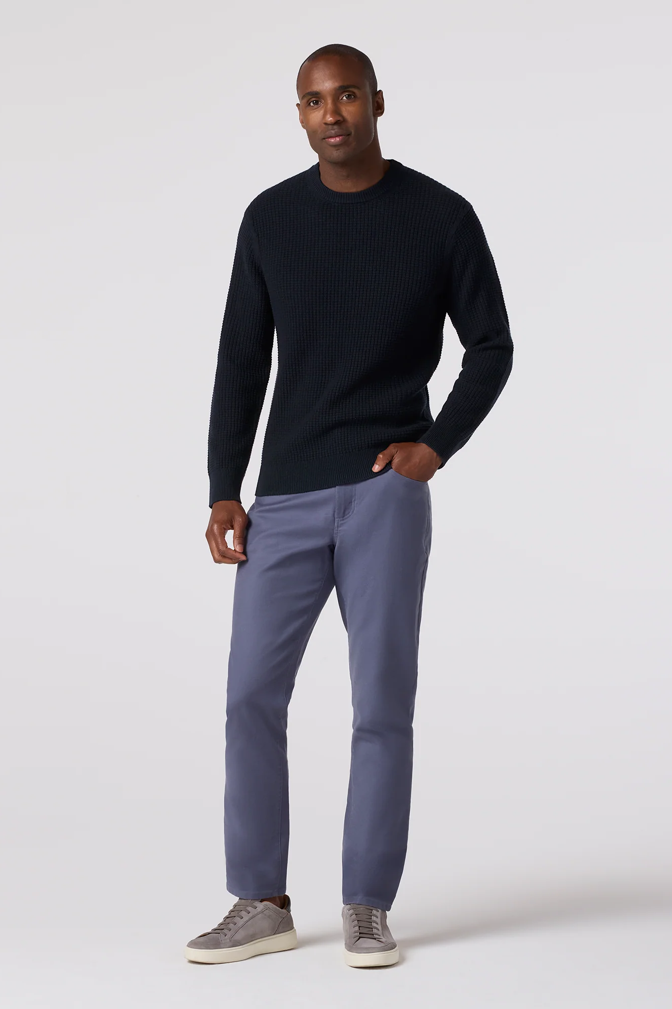 Man wearing a black sweater and gray pants on a white background