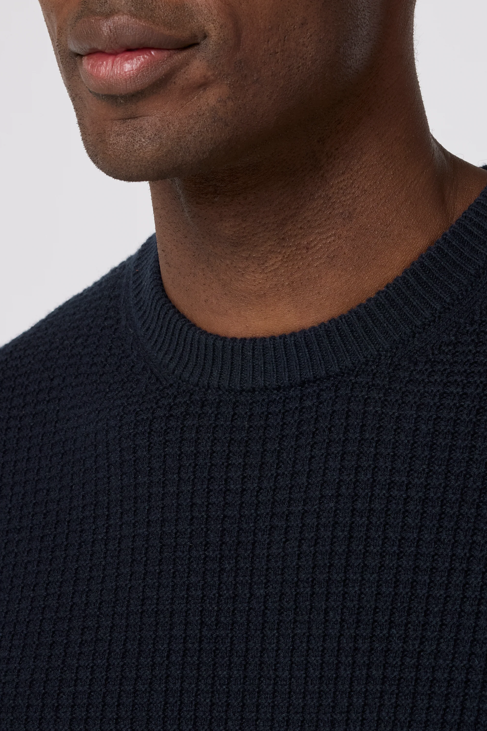 Close-up of a person wearing a navy blue sweater against a light gray background