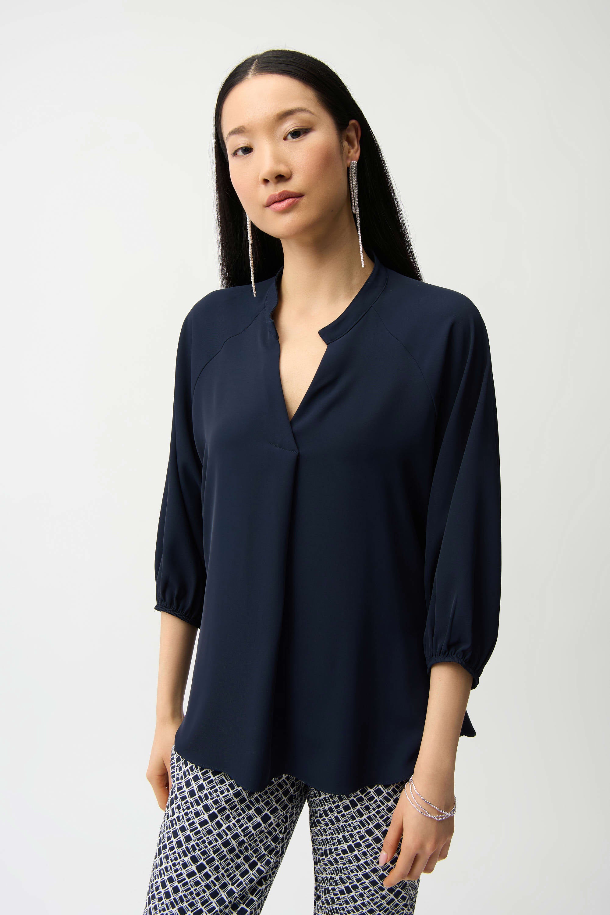 Woman wearing a navy blue blouse and patterned pants on a white background