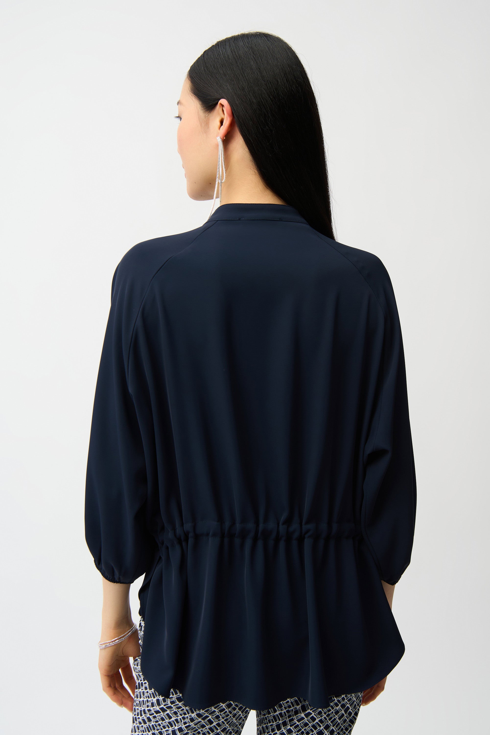 Person wearing a navy blue top with a plain background