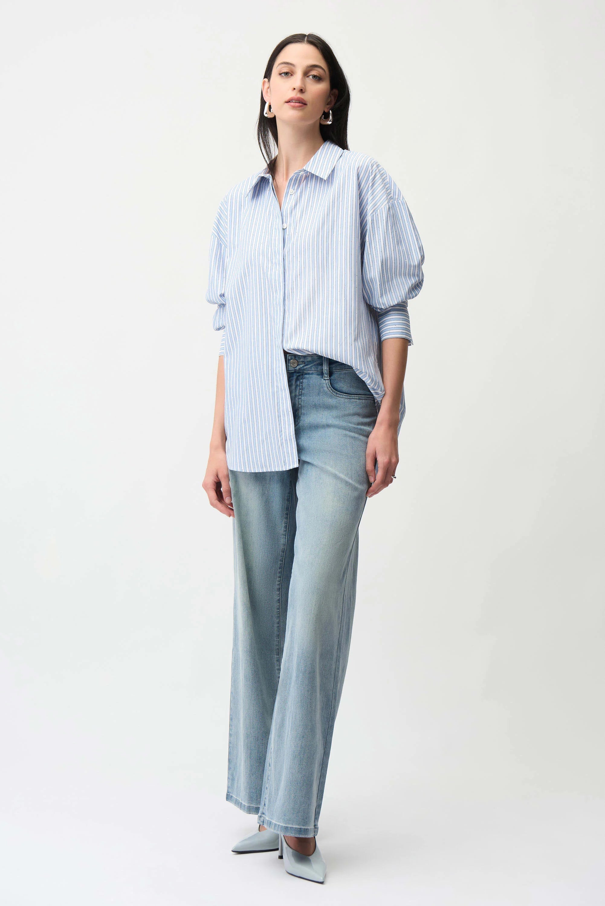 Woman wearing a light blue striped shirt and jeans on a white background