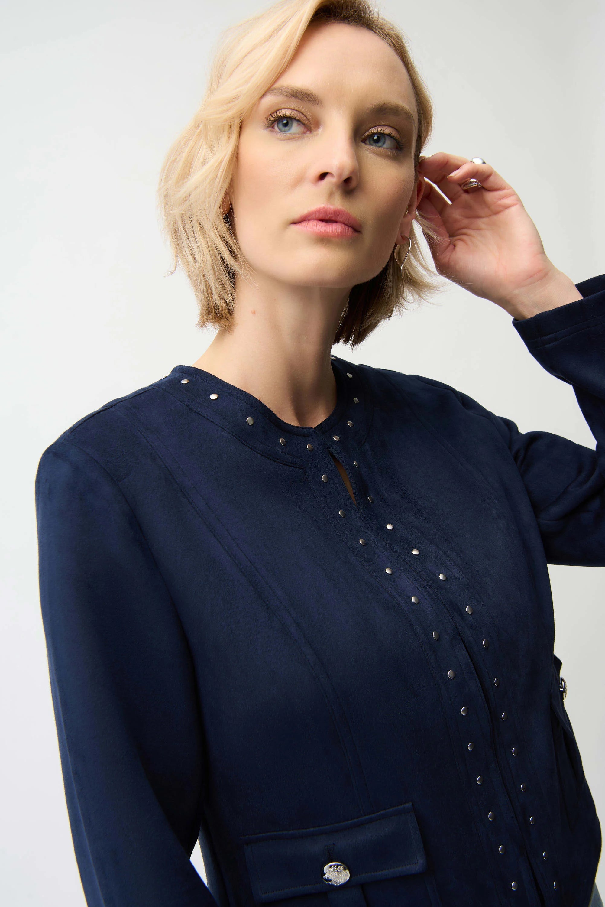 Woman wearing a navy blue dress with decorative elements on a plain background