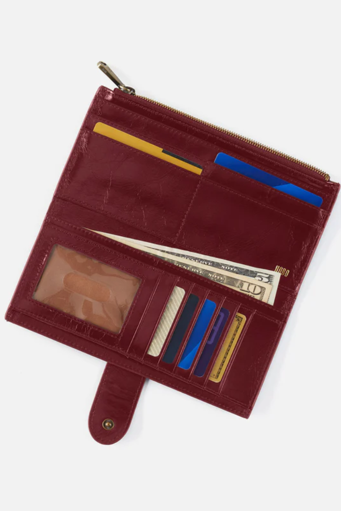 Open red leather wallet with various cards and money on a white background