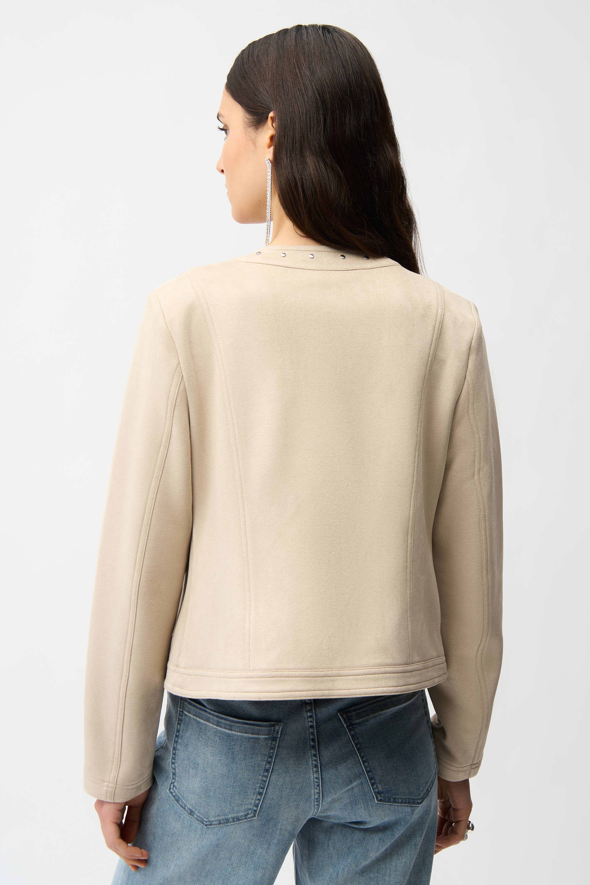 Woman wearing a beige jacket and blue jeans on a white background