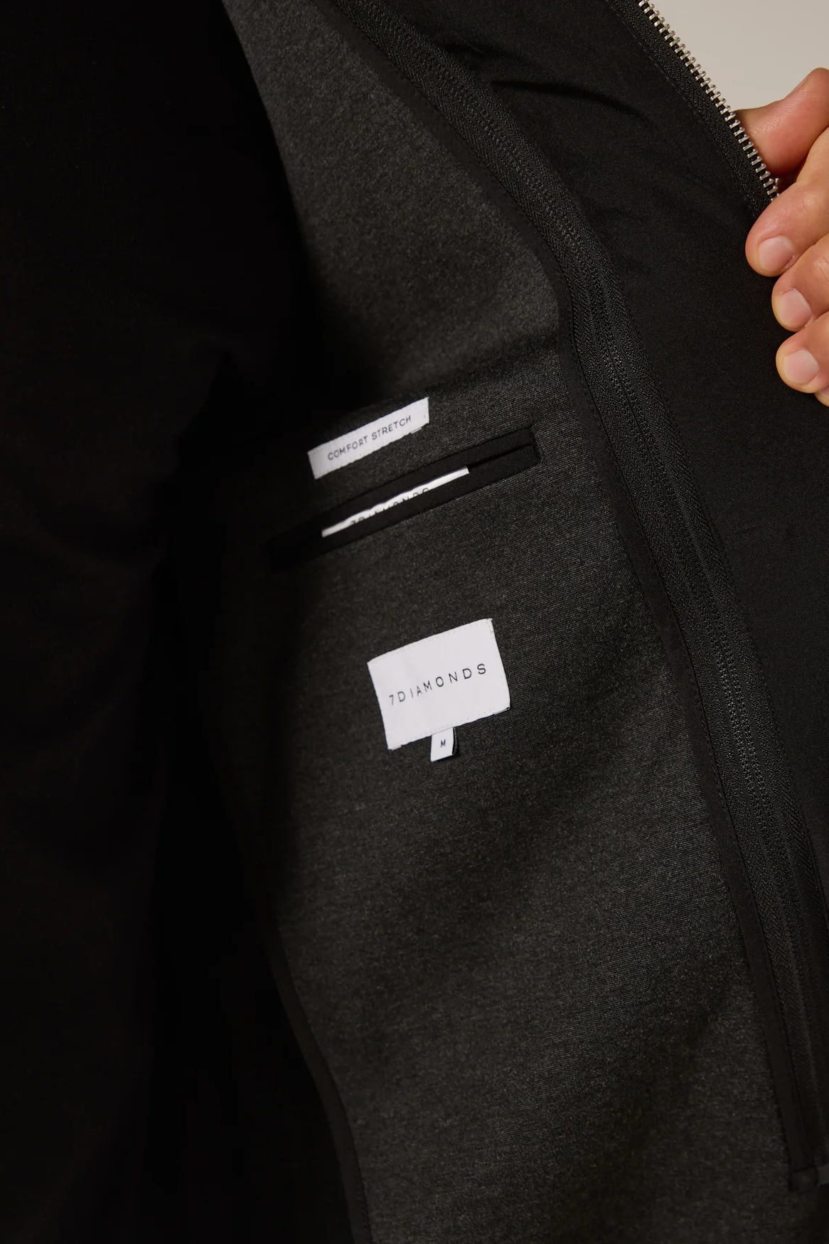 Close-up of a dark gray jacket with a brand label on the chest pocket.