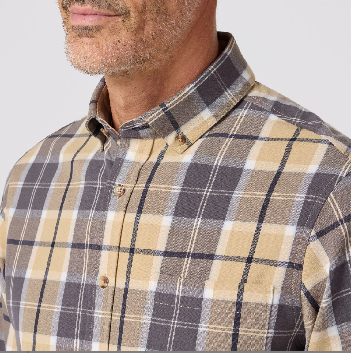 Man wearing a plaid shirt with a neutral background