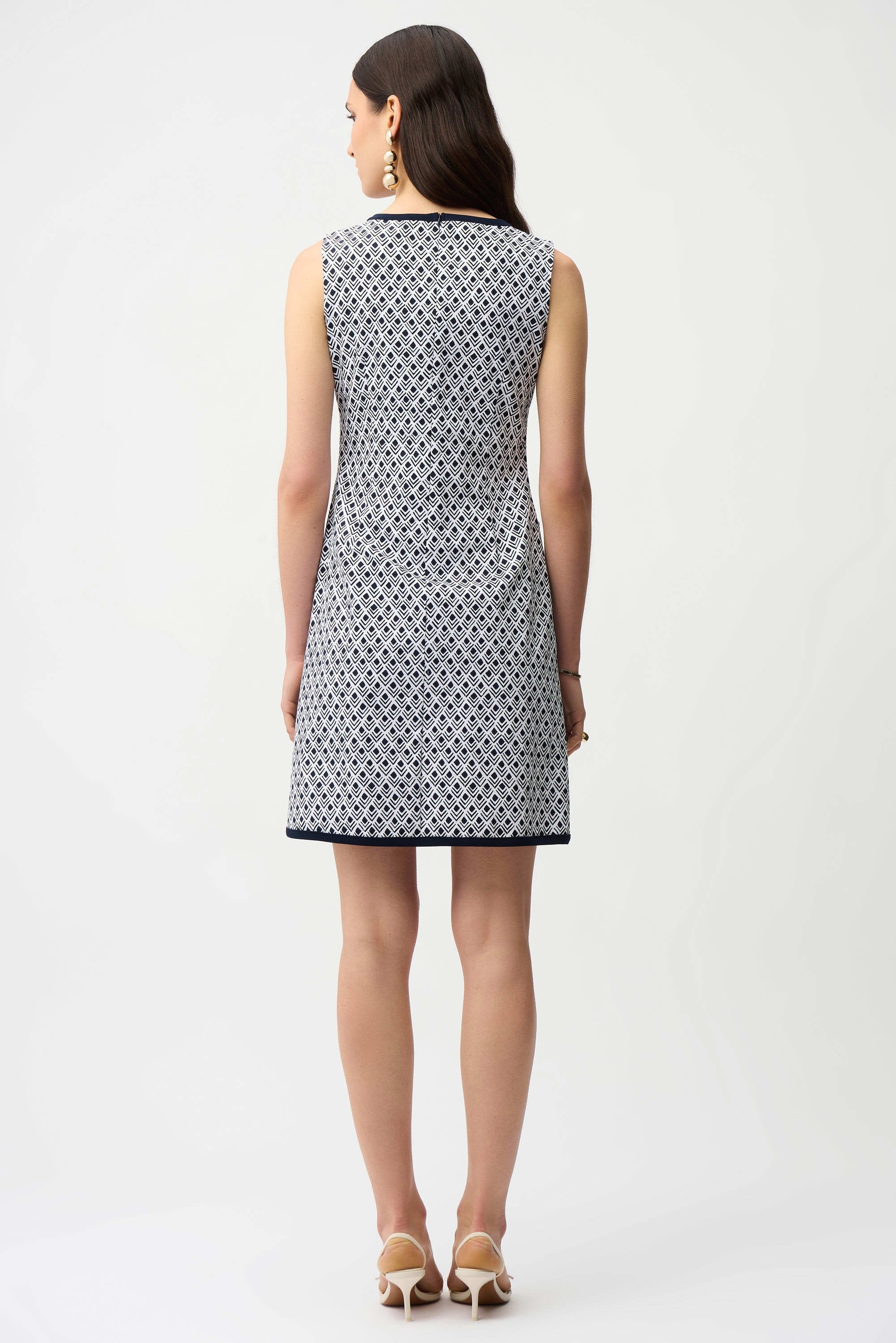 Woman wearing a sleeveless patterned dress on a white background