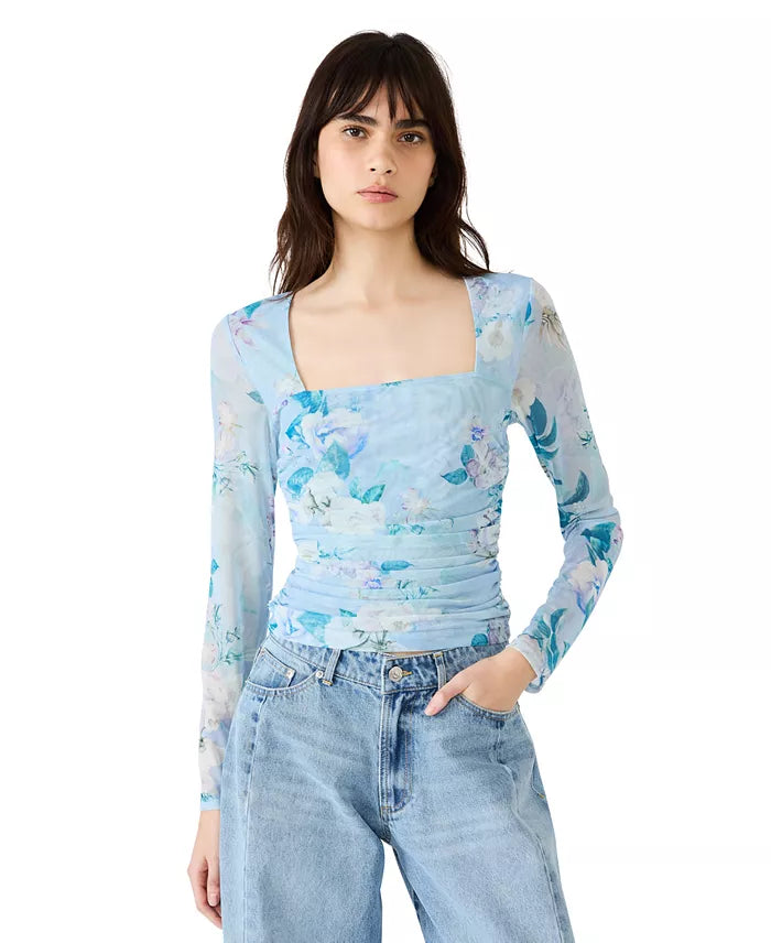 Woman wearing a floral long-sleeve top and jeans on a white background