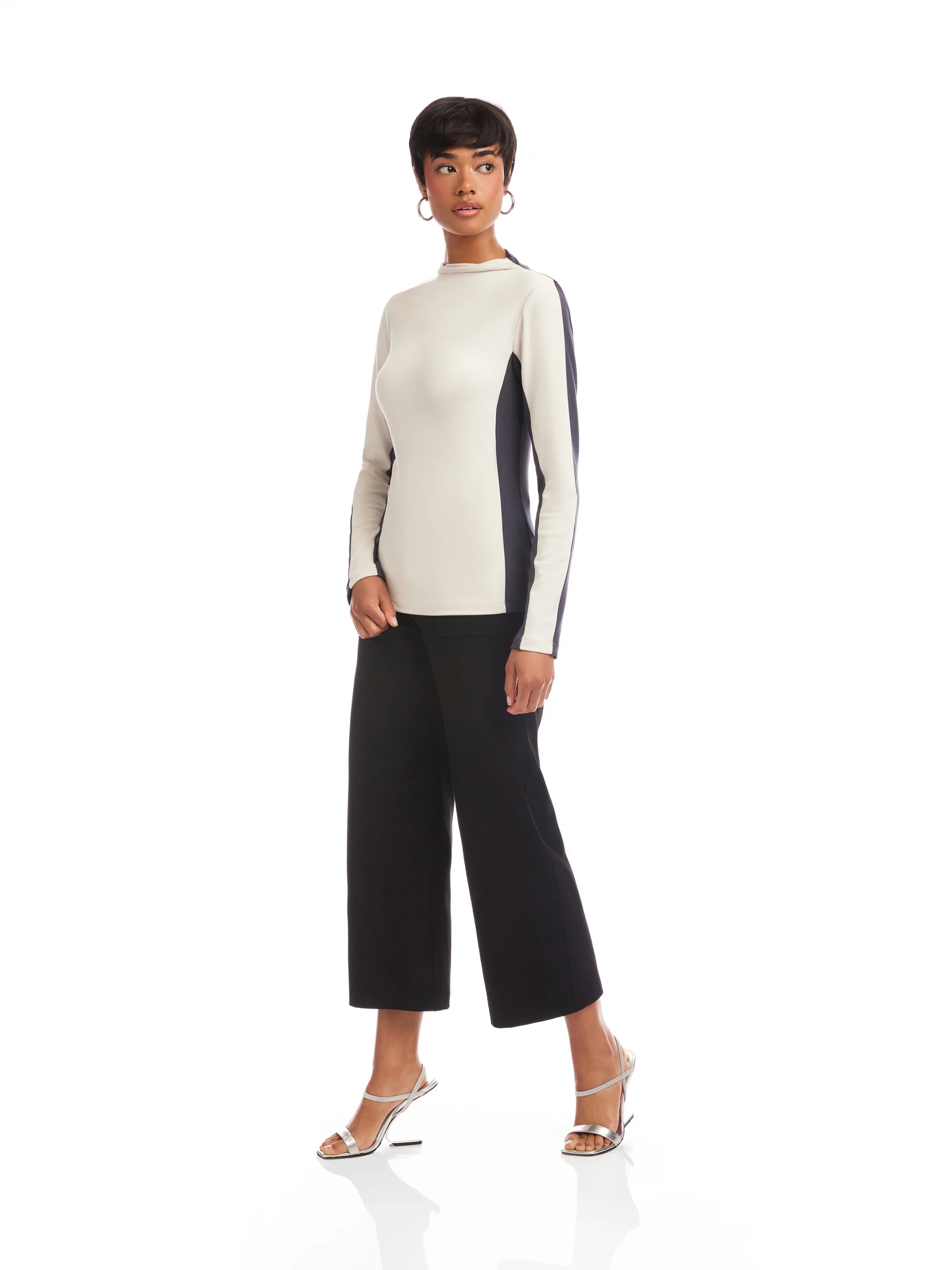 Woman wearing a two-tone sweater and black pants on a white background