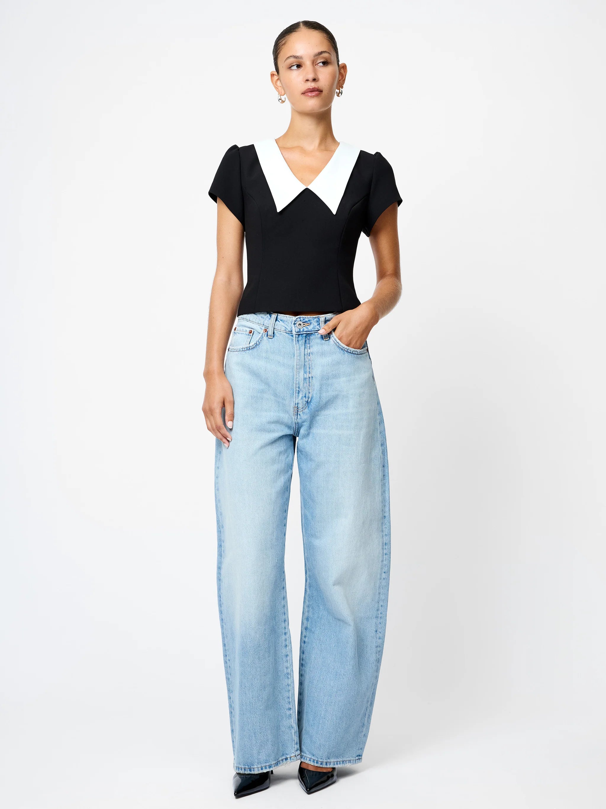 Woman wearing a black top and light blue jeans on a white background