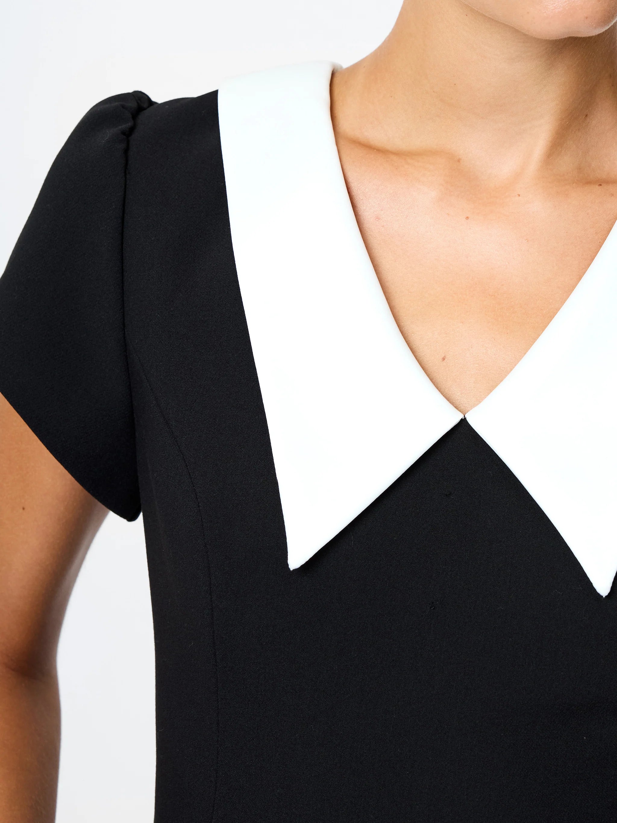 Black dress with a white collar on a plain background