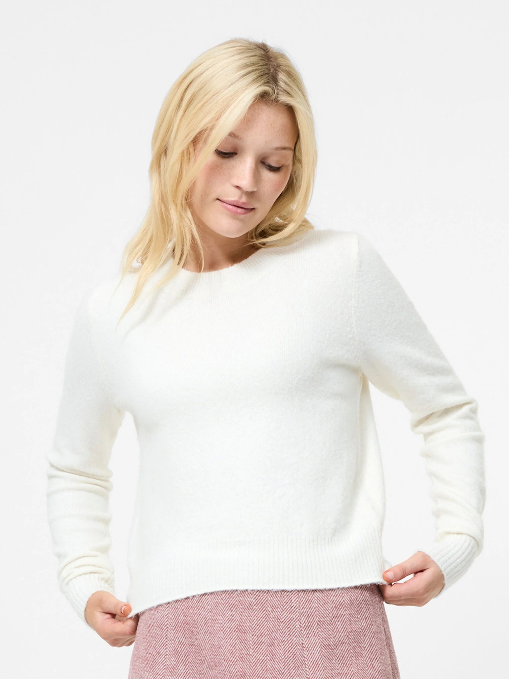 Woman wearing a white sweater on a plain background