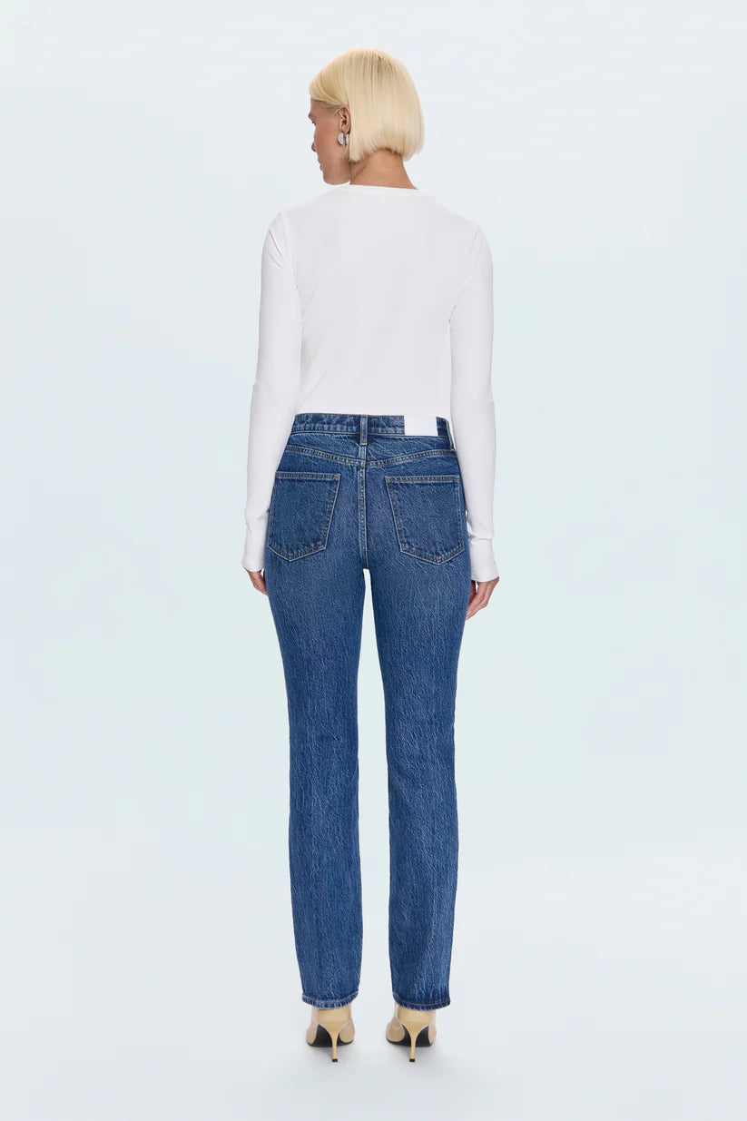 Person wearing blue jeans and a white top on a light blue background