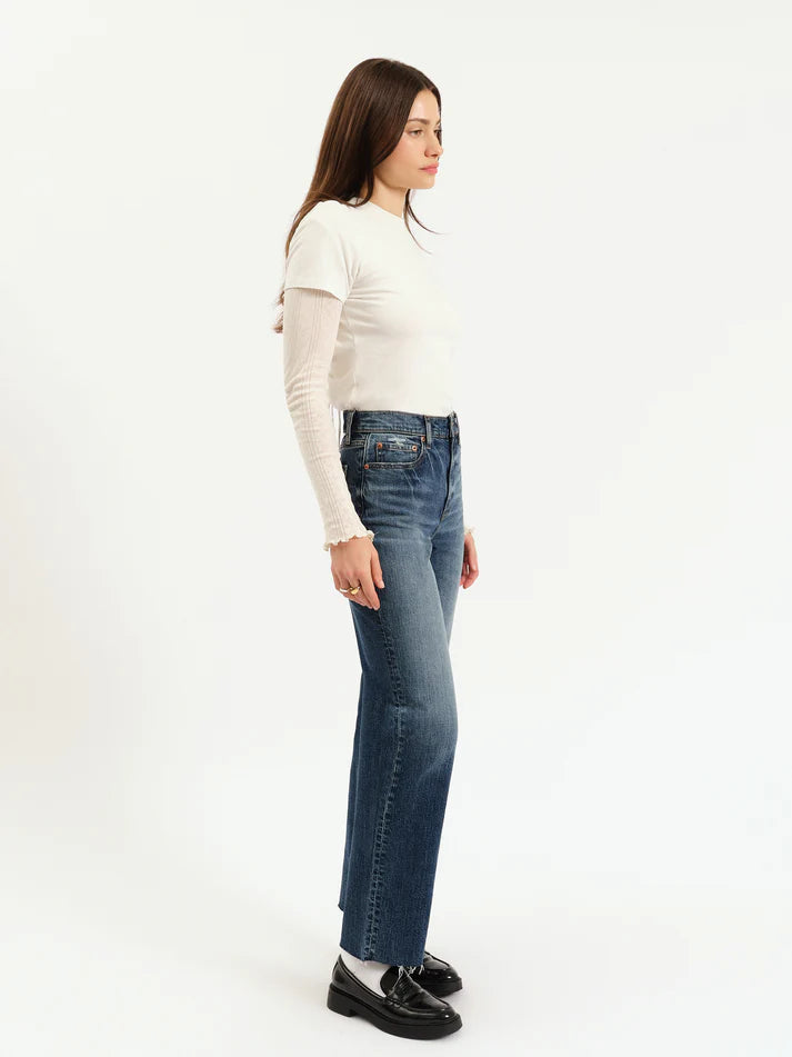 Woman wearing blue jeans and a white top on a white background