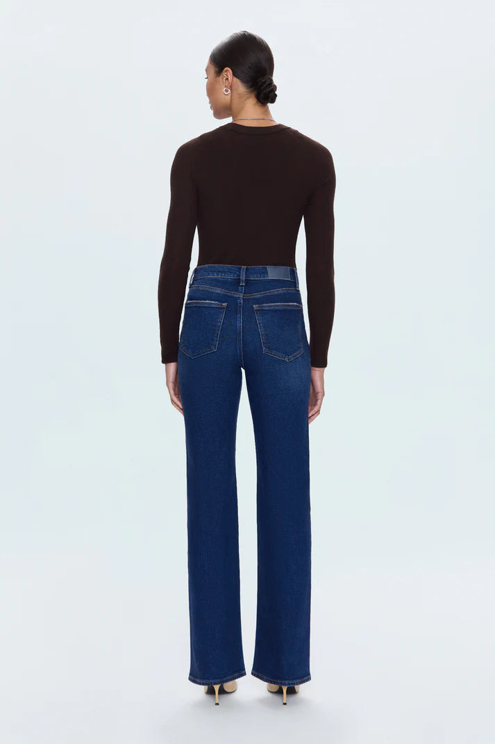 Person wearing blue jeans and a black long-sleeve top on a white background