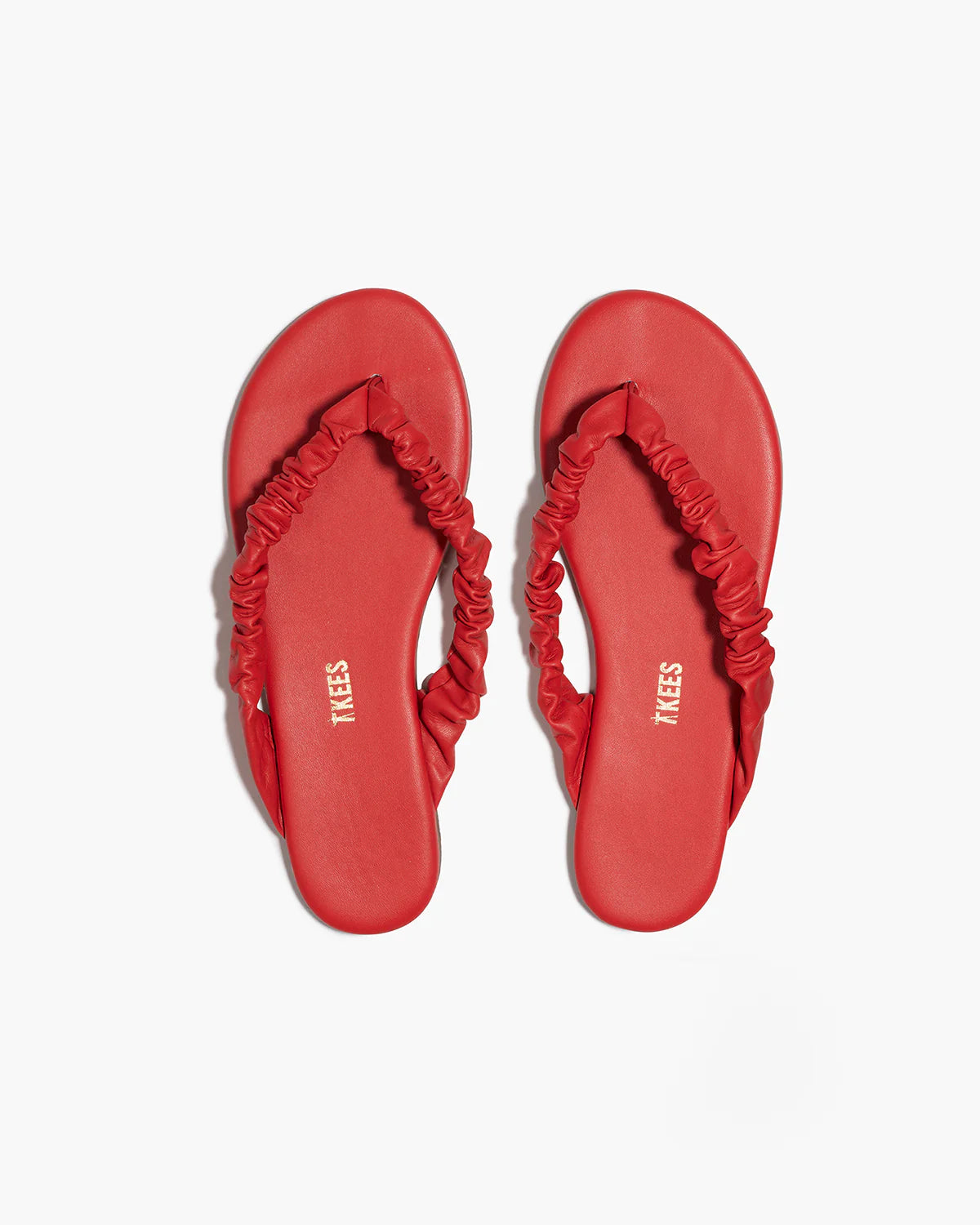 Red sandals with ruched straps on a white background
